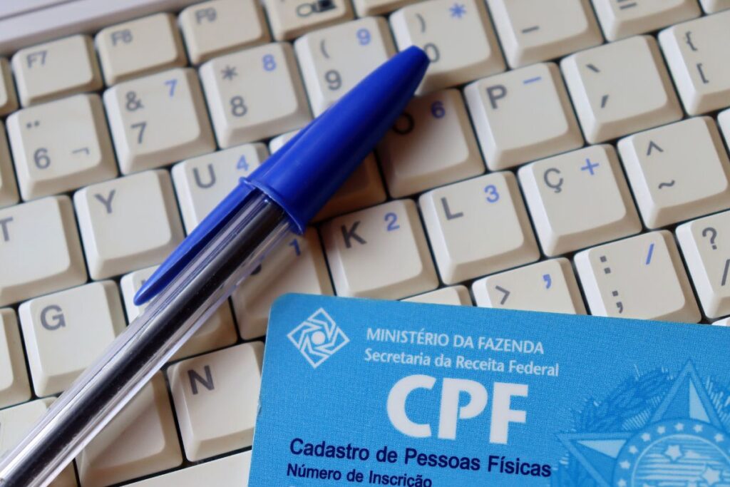 Imagem de um CPF e uma caneta bic e um teclado.
