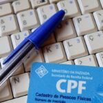 Imagem de um CPF e uma caneta bic e um teclado.