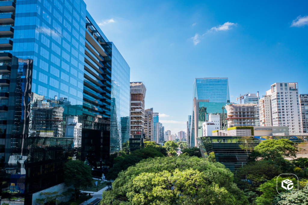 Centro corporativo moderno espelhado com árvores sob céu azul ensolarado.